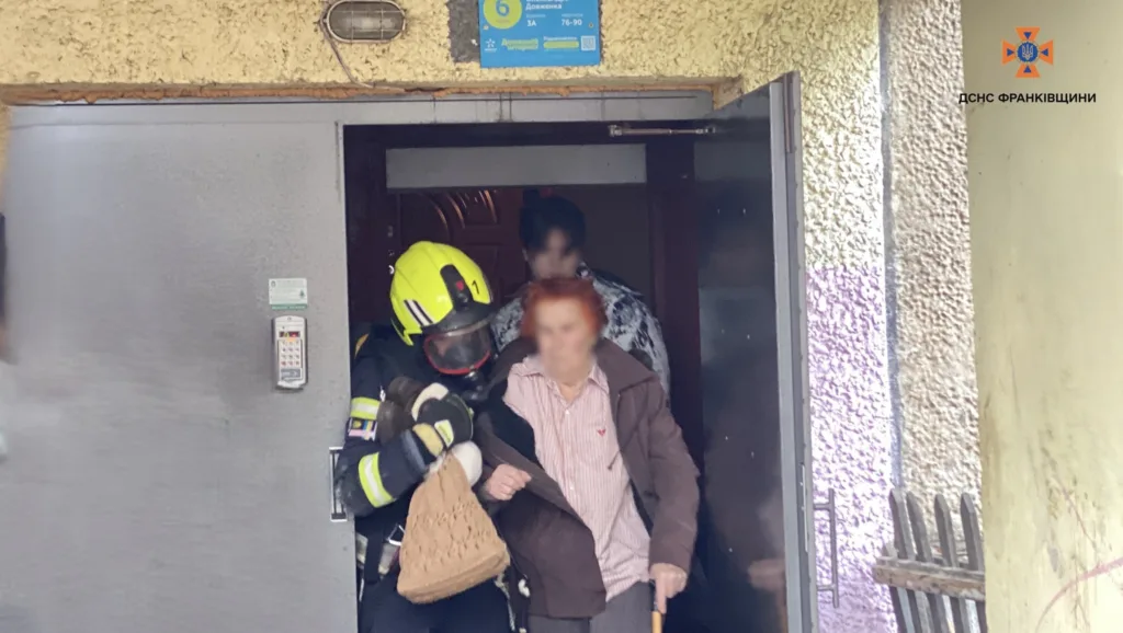 Рятувальник допомагає літній жінці вийти з будинку