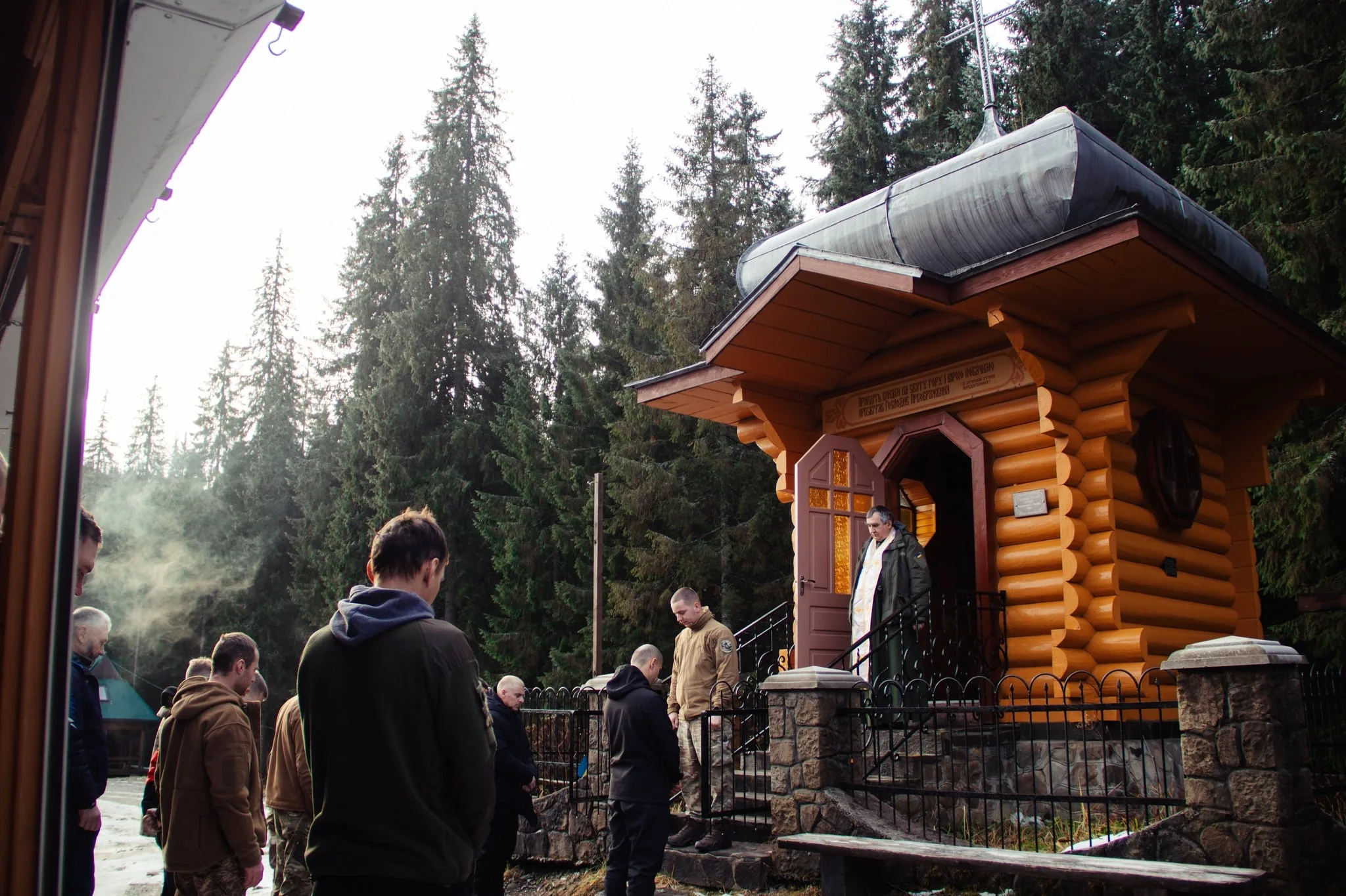 Люди моляться біля дерев'яної каплиці в лісі
