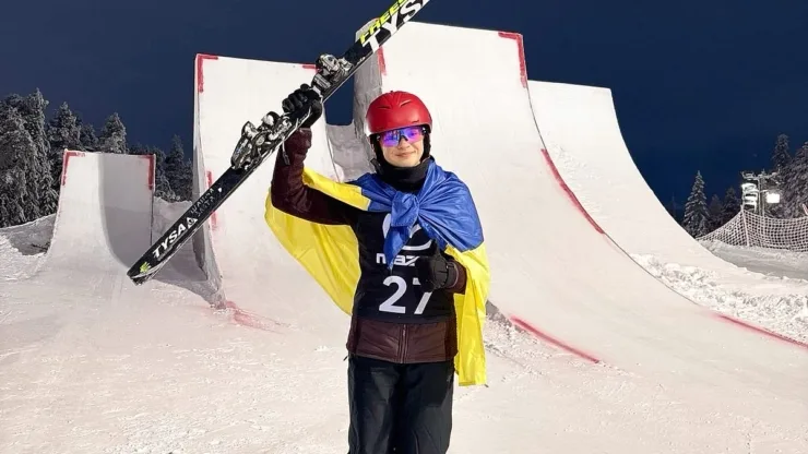 Лижник з українським прапором на сніжному трампліні