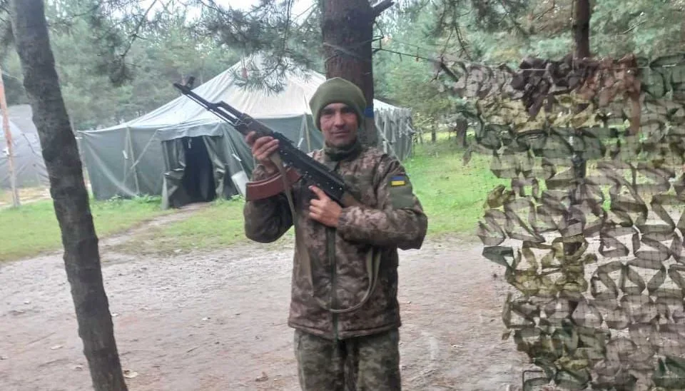 Український військовий у камуфляжі тримає зброю в лісі