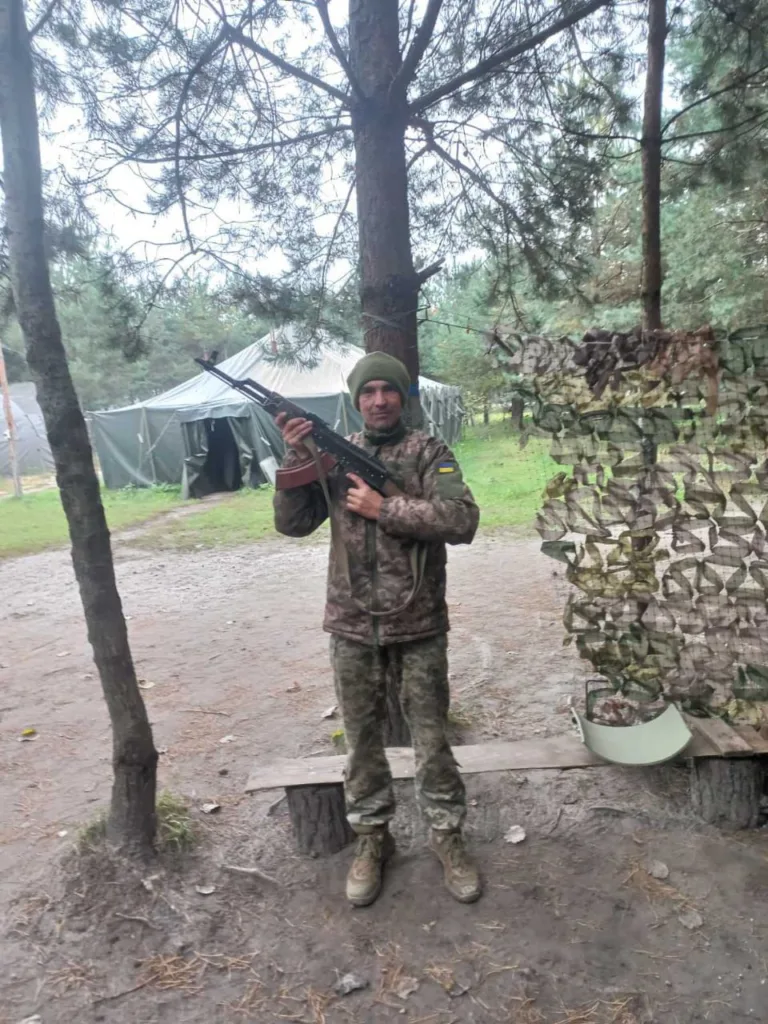 Військовий у камуфляжі стоїть у лісі з автоматом