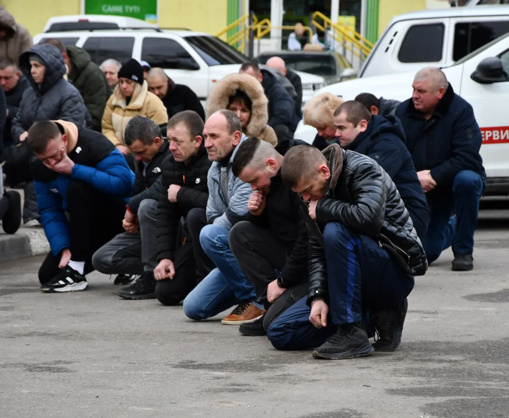 Люди на колінах під час вуличної церемонії