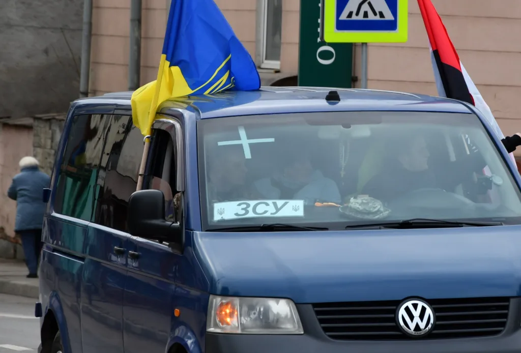 Синій мікроавтобус з українськими прапорами на вулиці