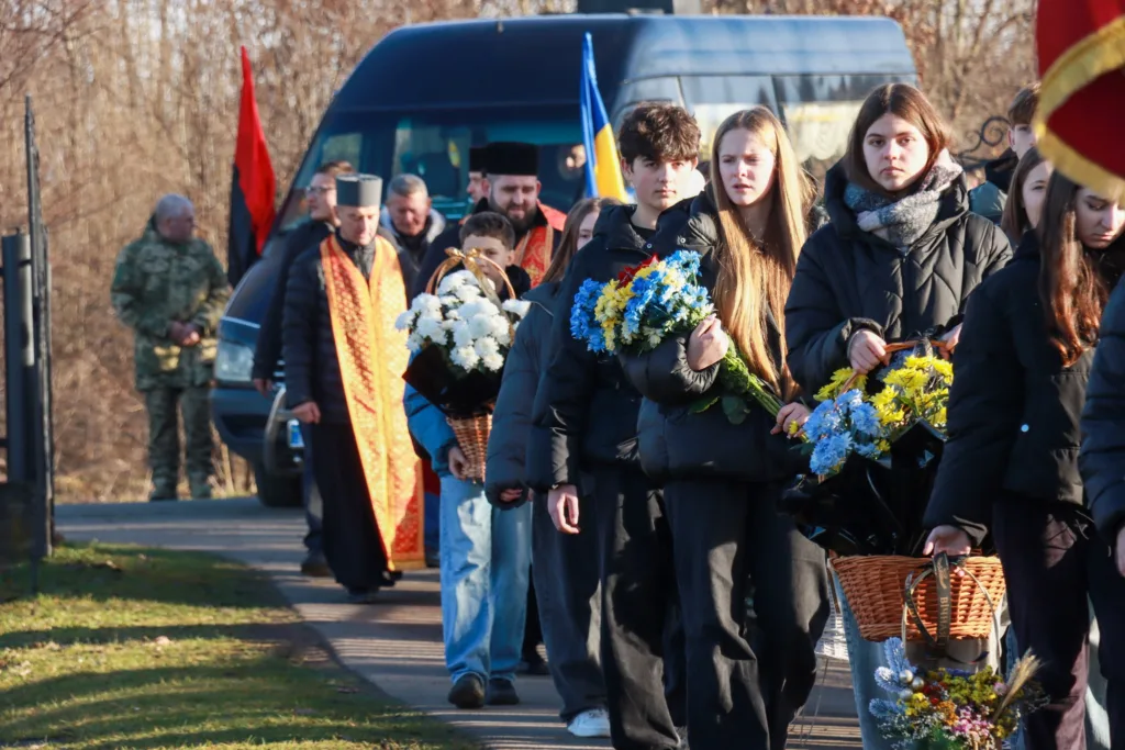 Люди несуть квіти на траурній церемонії
