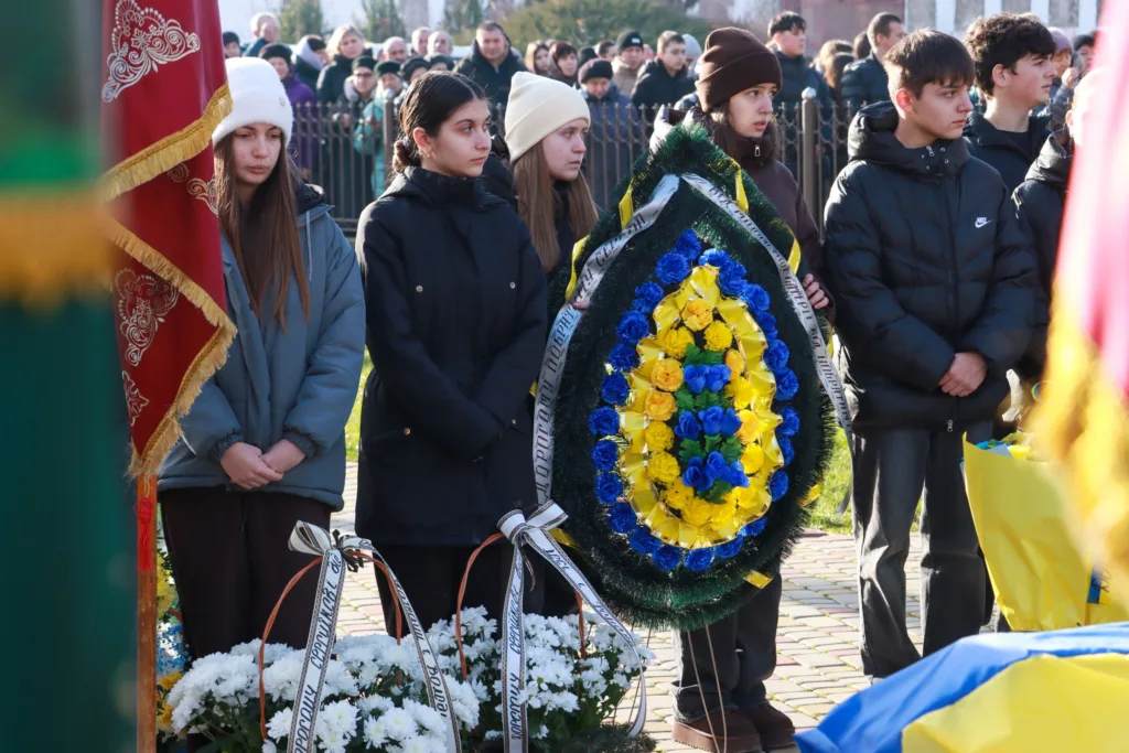 Люди на церемонії вшанування з квітами та вінками