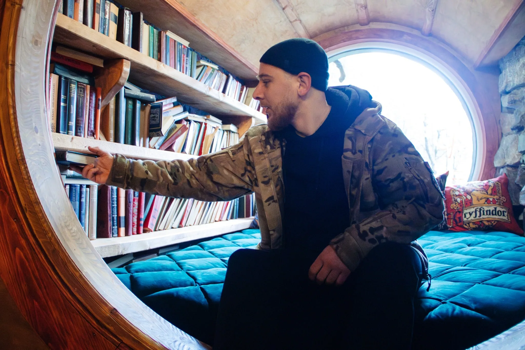 Чоловік вибирає книгу з полиці біля вікна