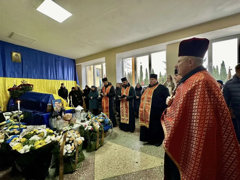 Похоронна церемонія з українським прапором і священниками