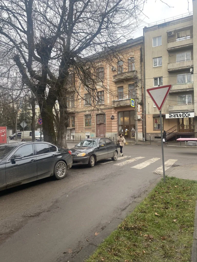 Жінка переходить дорогу біля старих будинків