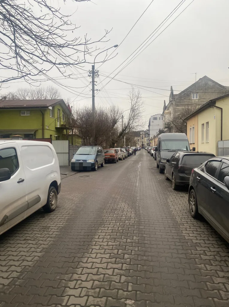 Міська вулиця з припаркованими автомобілями вздовж тротуару