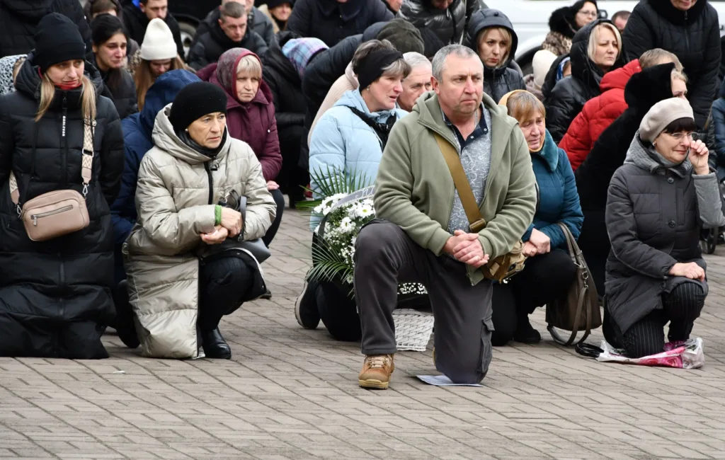 Люди стоять на колінах під час жалобної церемонії