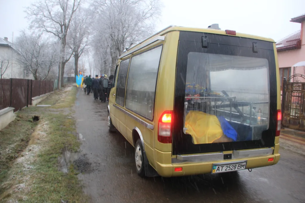 Похоронна процесія з українським прапором на вулиці