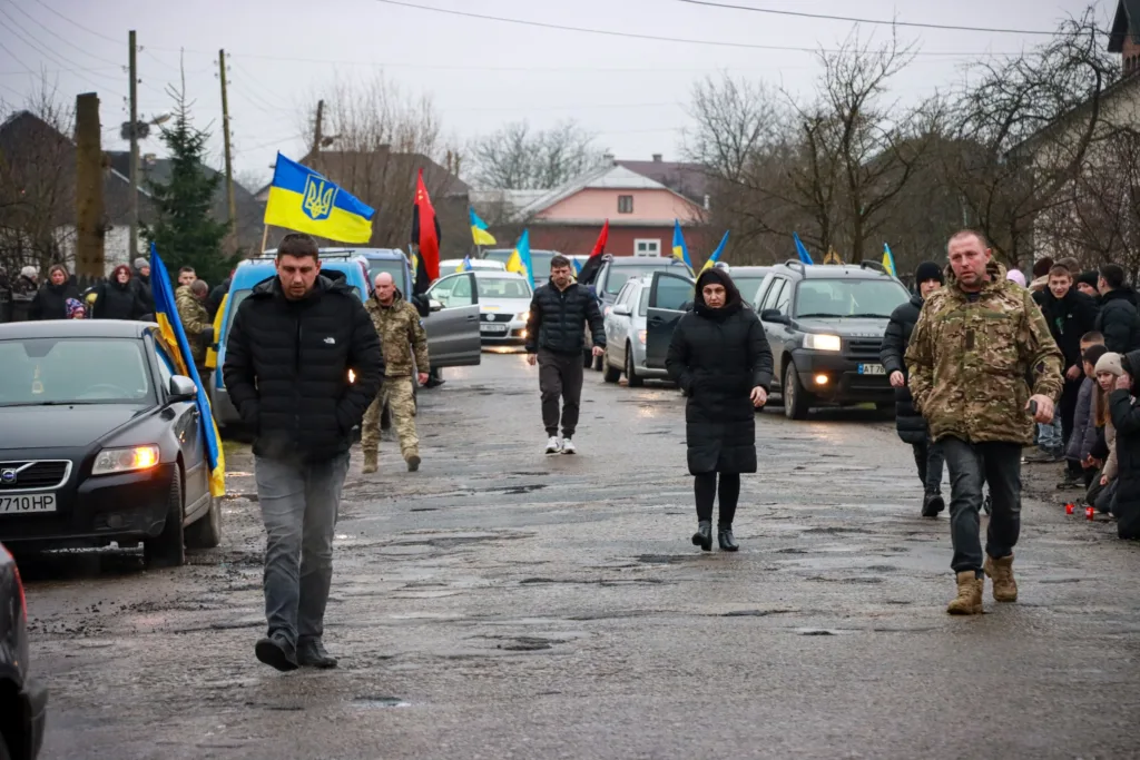 Люди йдуть вулицею з українськими прапорами