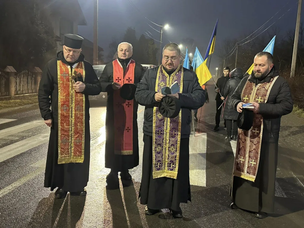 Священики моляться на вулиці з українськими прапорами