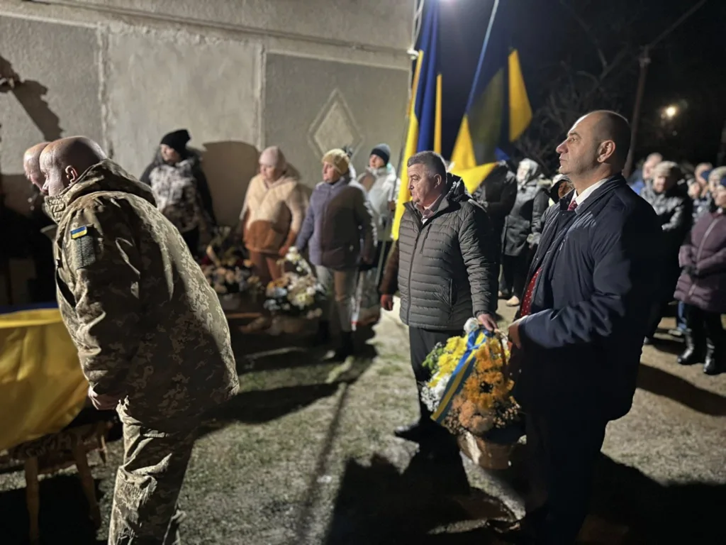 Люди на меморіальній церемонії з українськими прапорами