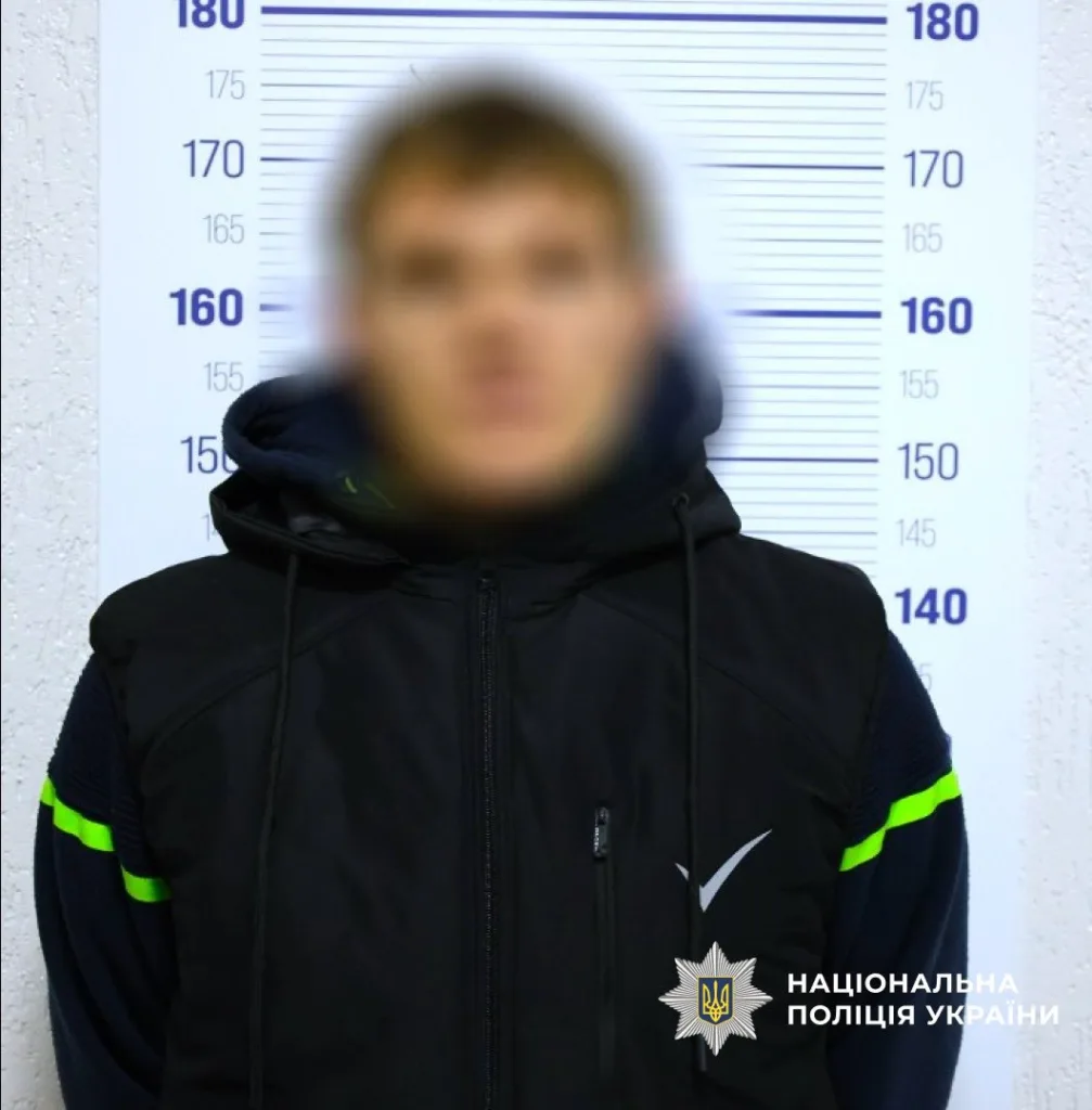 Затримана особа перед фоном поліції України