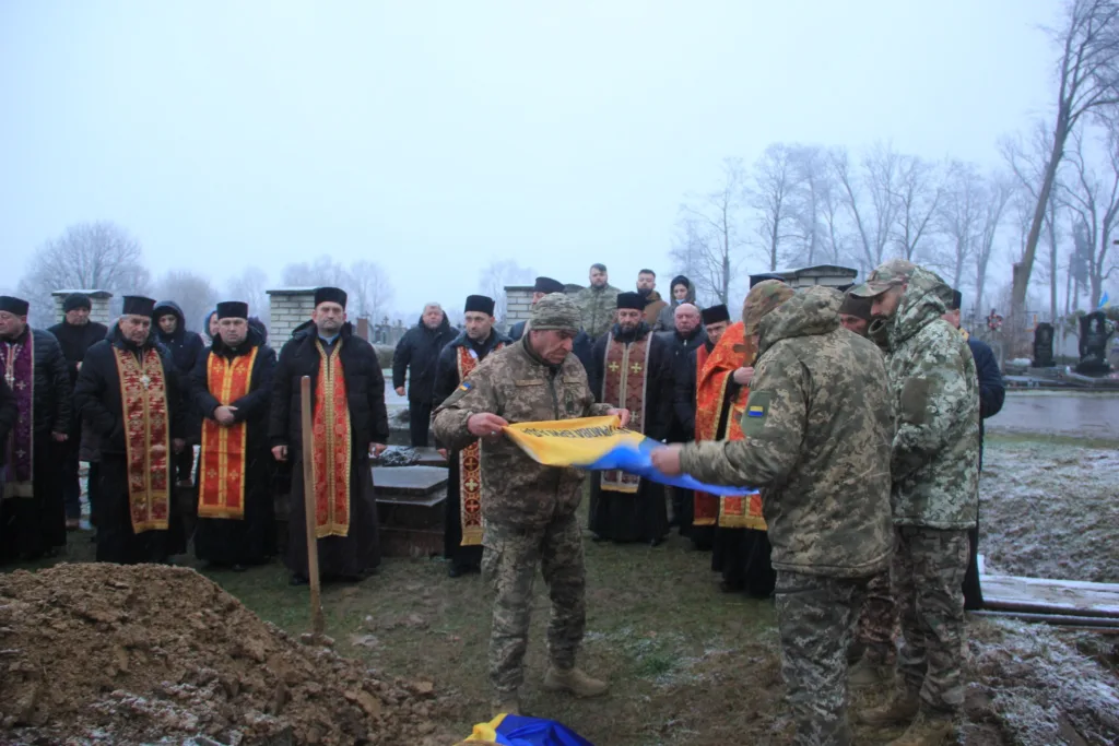 Військові складають прапор на похороні героя