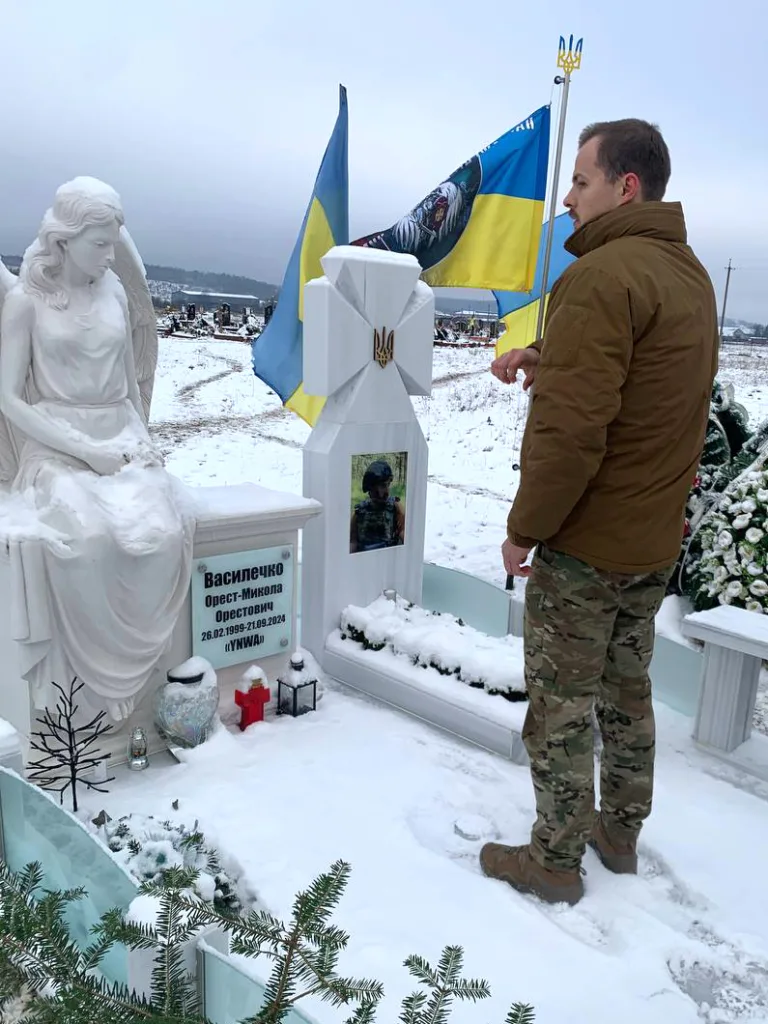 Чоловік вшанувує пам’ять на кладовищі взимку