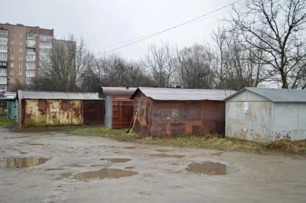 Ряд іржавих гаражів біля багатоповерхівки