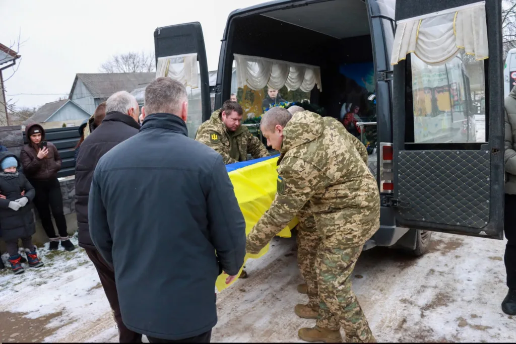 Військові несуть труну, накриту українським прапором