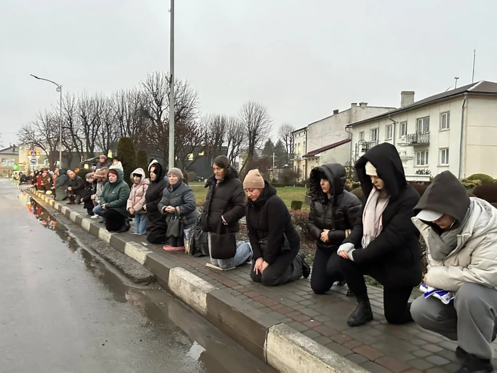 Люди стоять на колінах вздовж вулиці
