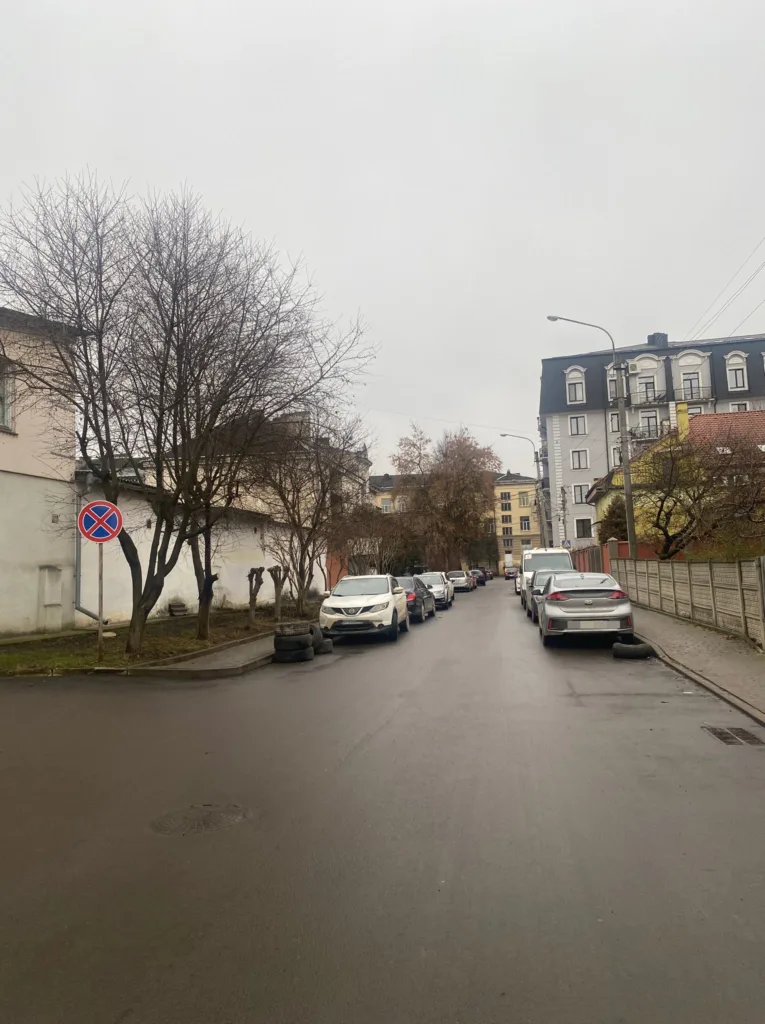 Вузька міська вулиця з припаркованими автомобілями