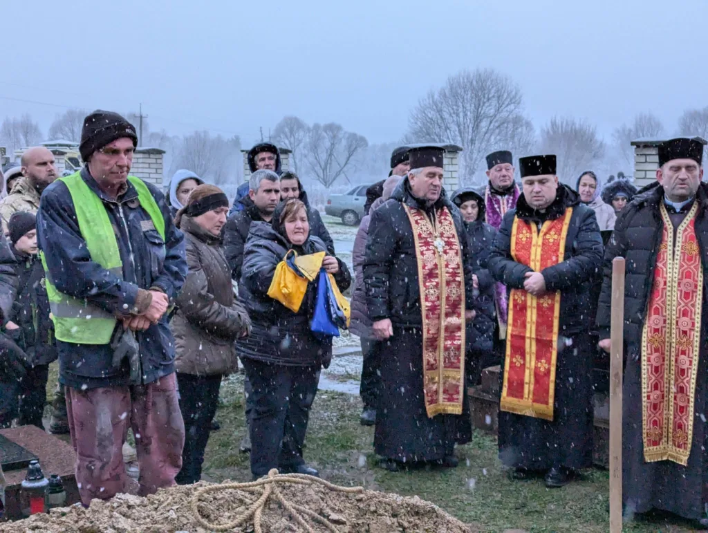 Люди на похороні під час снігопаду