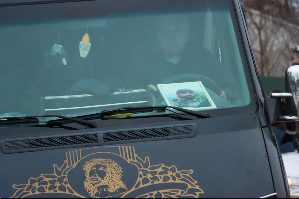 Водій у машині з фотографією військового на панелі