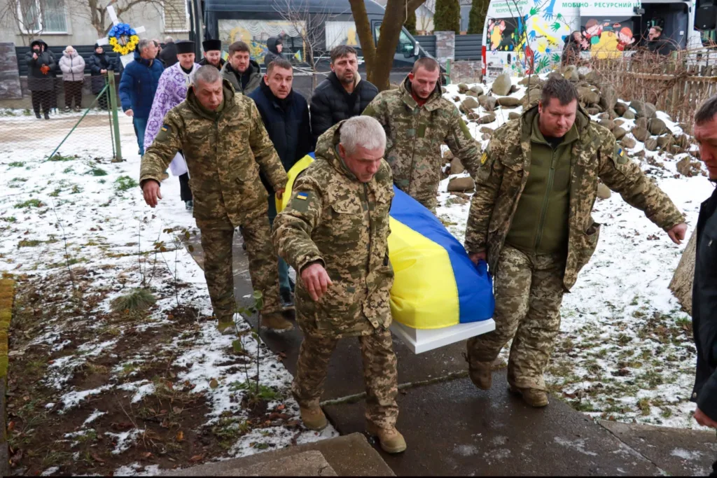 Військові несуть труну, накриту українським прапором