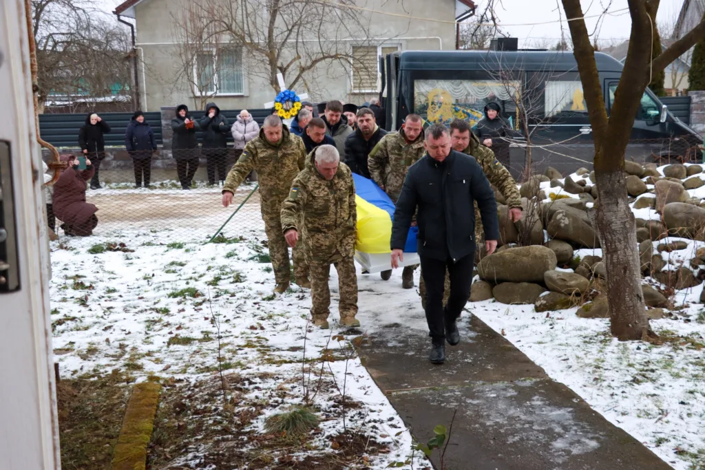 Військові несуть труну, накриту українським прапором