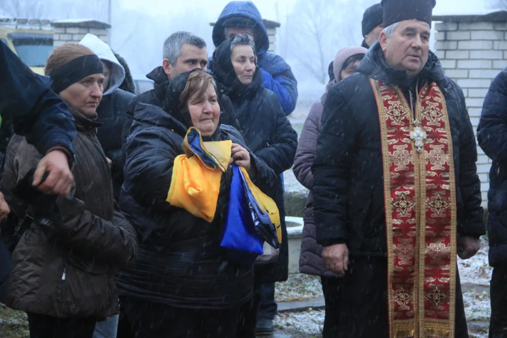 Люди на вулиці під снігом з українським прапором