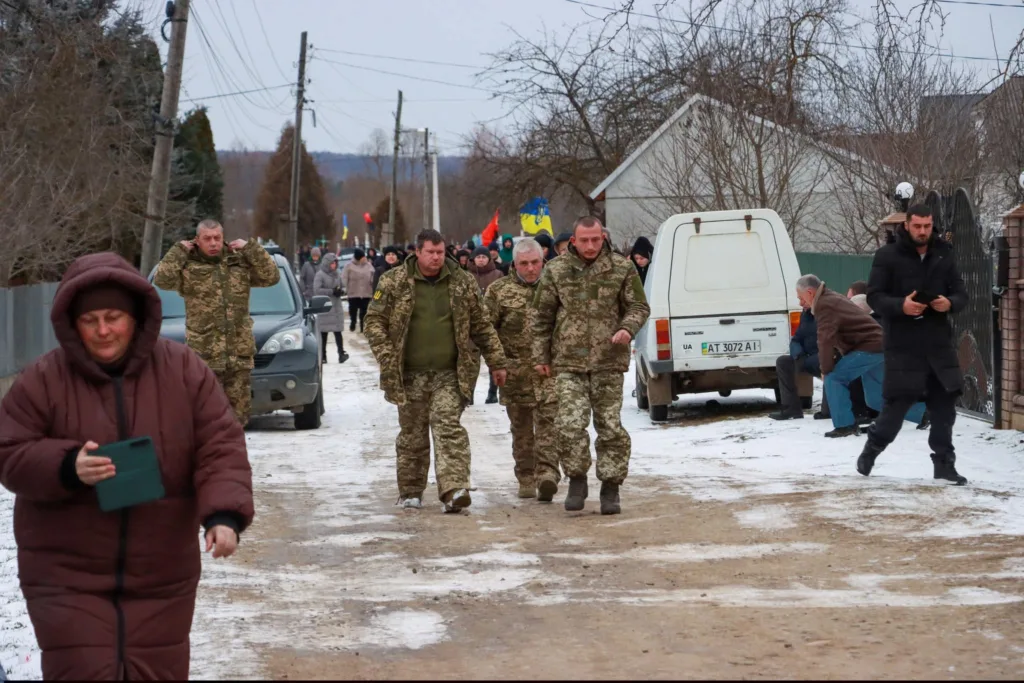 Військові та мешканці йдуть зимовою вулицею села