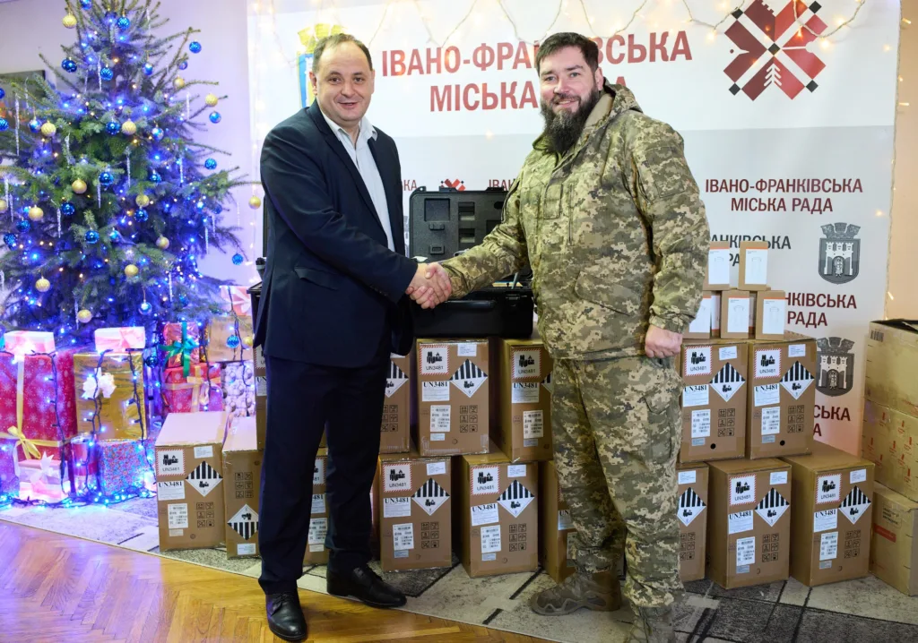 Військовий та посадовець тиснуть руки біля подарунків