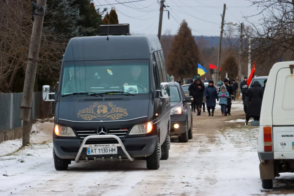 Процесія з прапорами й автомобілями на сільській дорозі