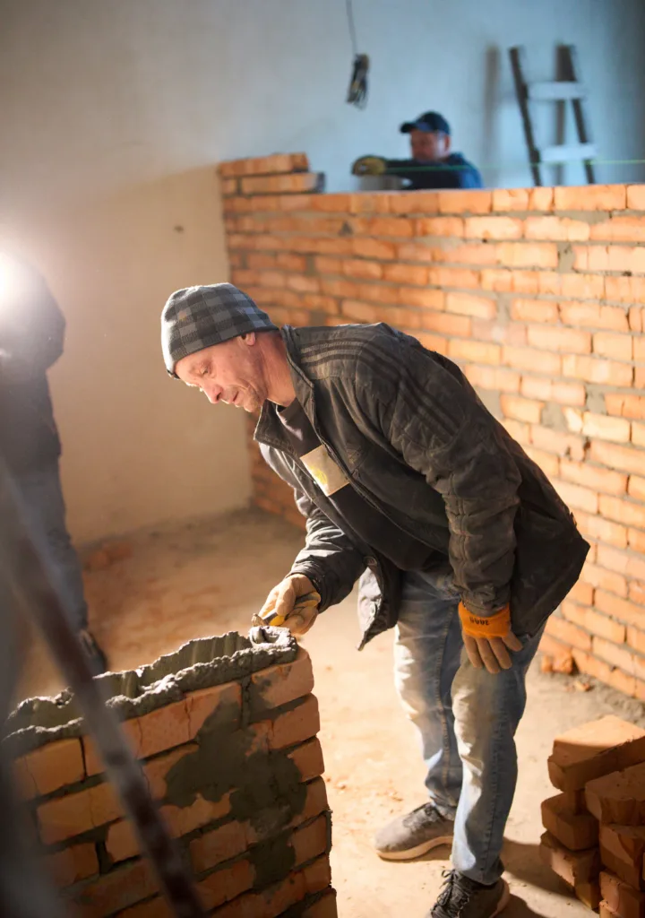 Будівельник мурує стіну з червоної цегли