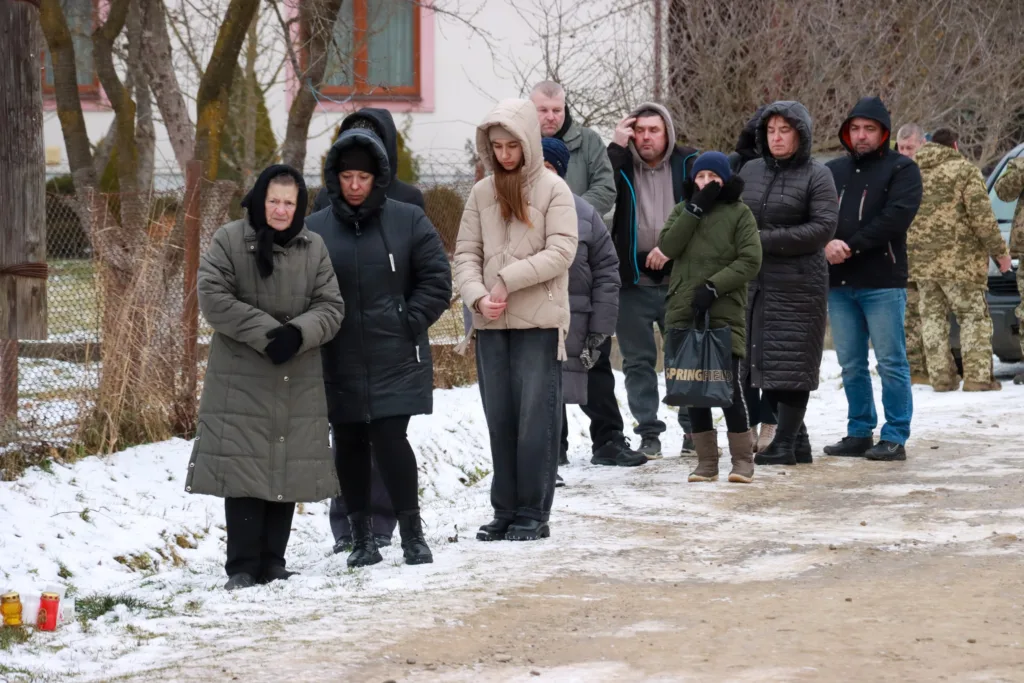 Люди стоять надворі взимку під час церемонії