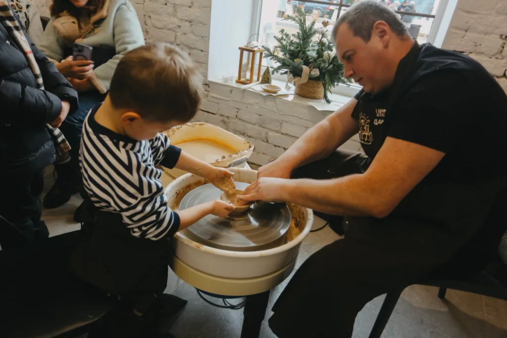 Дитина вчиться гончарству з майстром