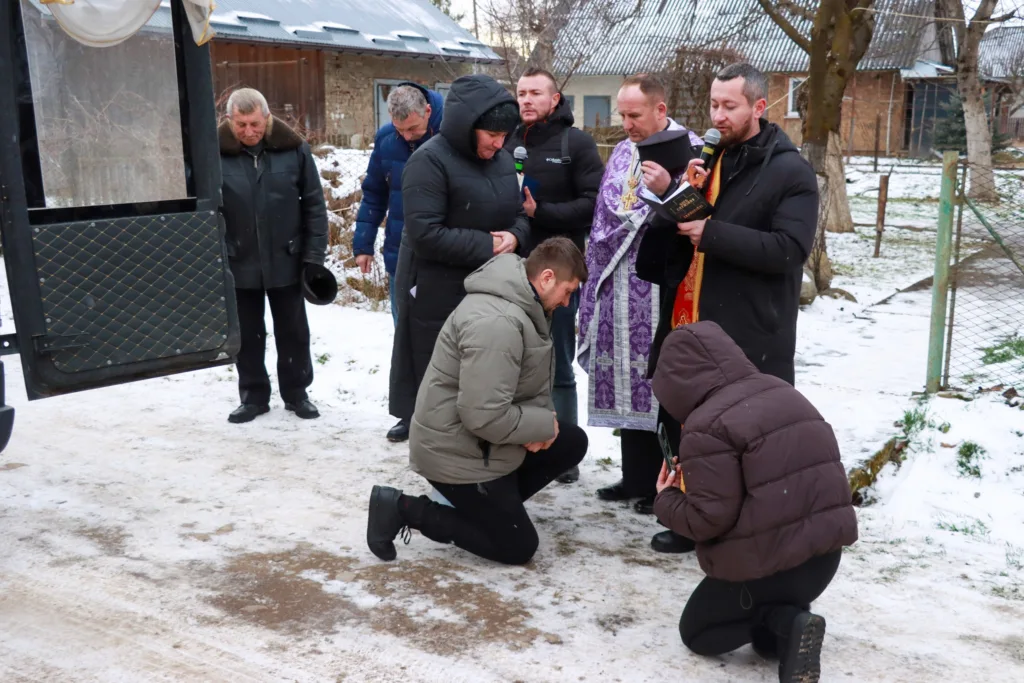 Священник молиться з людьми на снігу