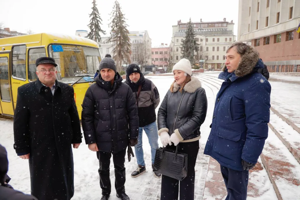 Люди розмовляють на снігу біля жовтого автобуса