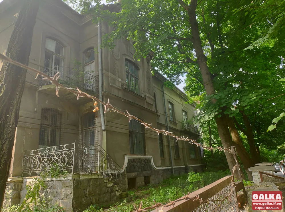 Стара будівля за колючим дротом серед дерев