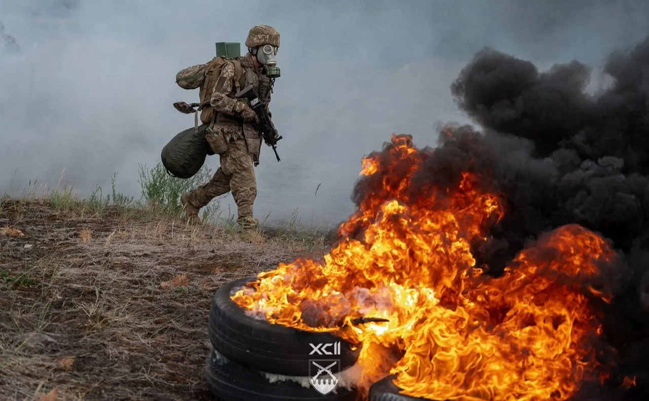 Військовий у диму біля палаючих шин