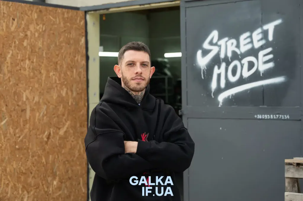 Чоловік у чорній худі біля графіті Street Mode