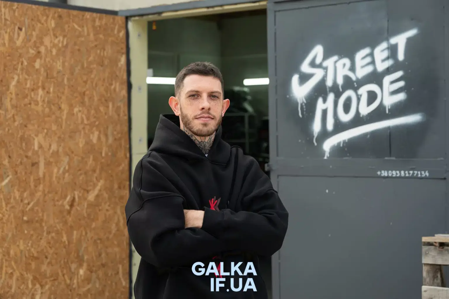 Чоловік у чорній худі біля графіті Street Mode