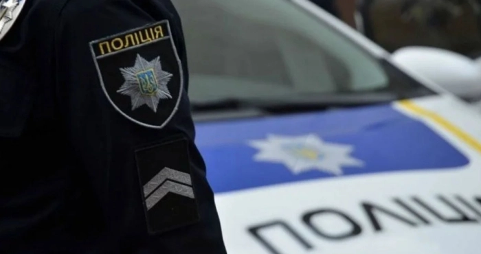 Поліцейський поруч із патрульним автомобілем України