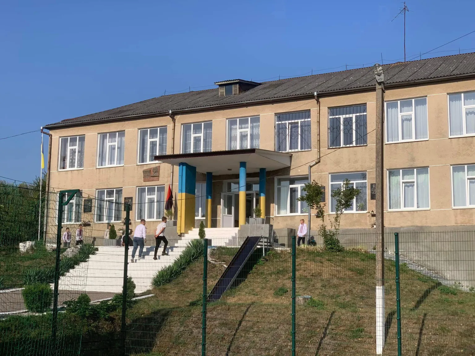 Двоповерхова шкільна будівля з українським прапором