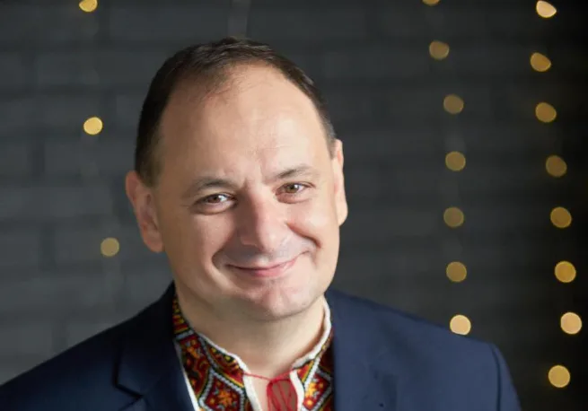 Чоловік у вишиванці усміхається на темному фоні