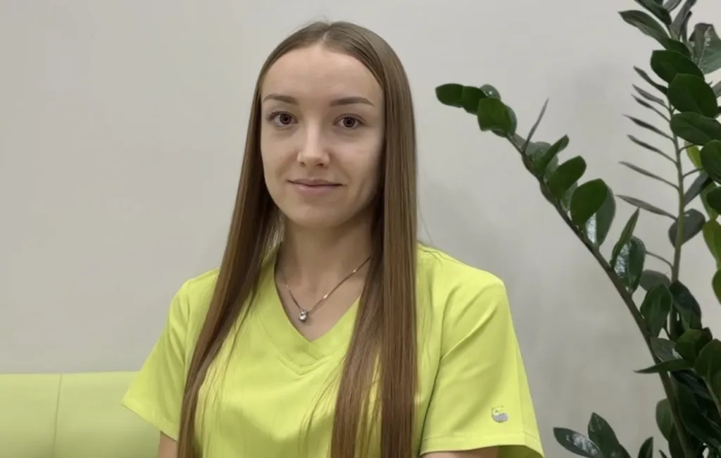 Жінка у жовтій формі сидить біля рослини