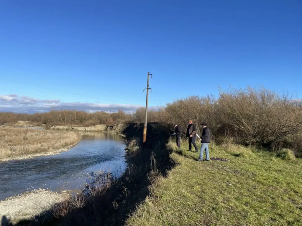 Люди стоять біля річки під синім небом