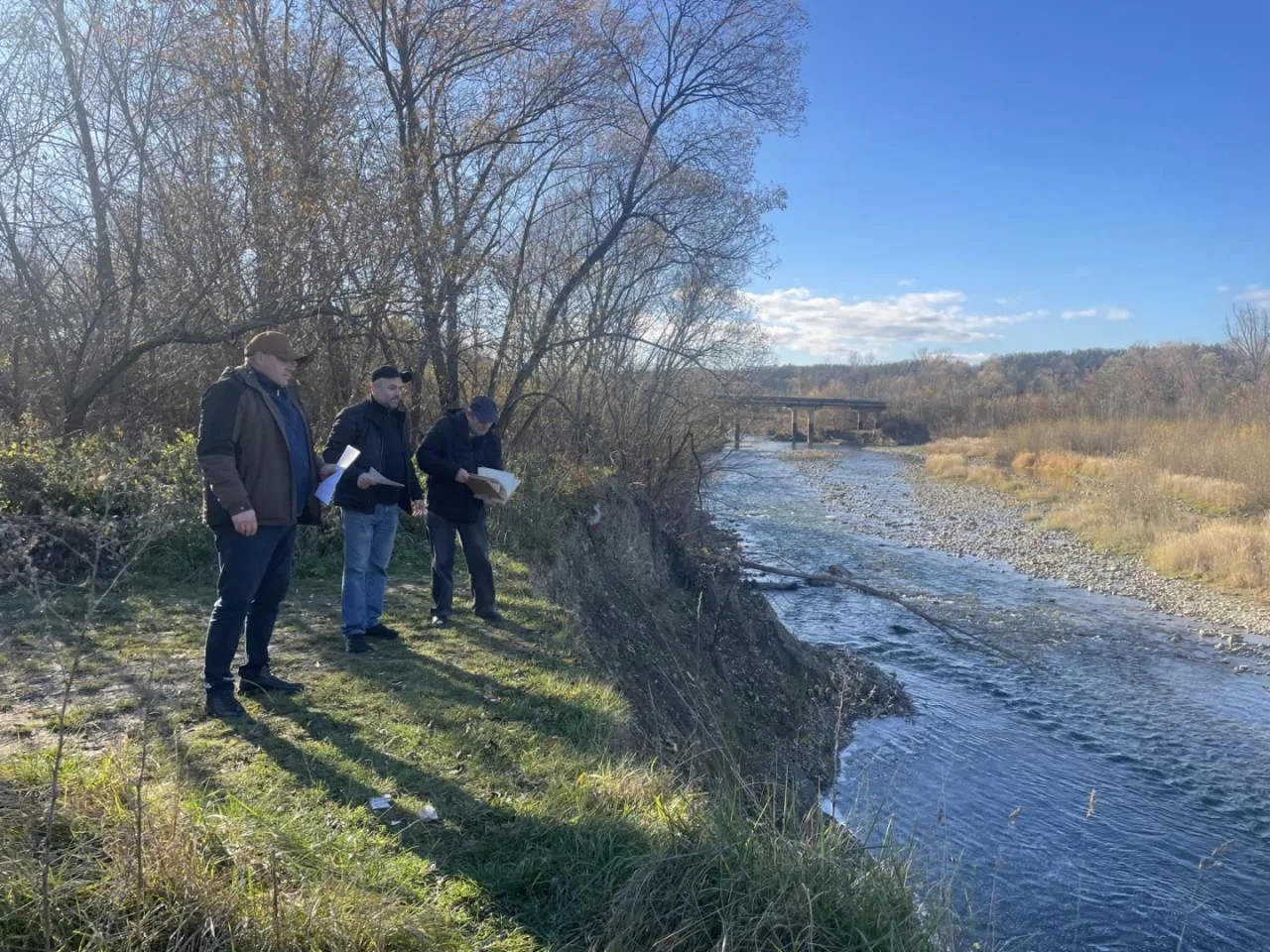 Люди оглядають річку біля моста восени