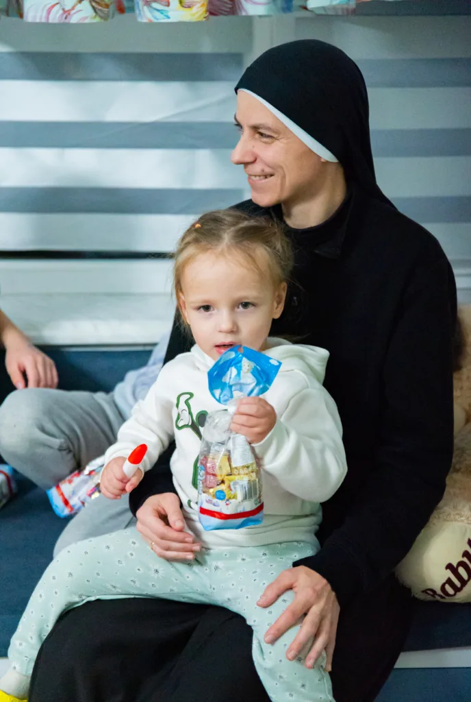 Жінка тримає дитину з солодощами на колінах