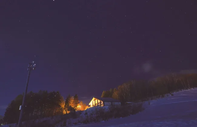 Будинок серед снігу під зоряним нічним небом